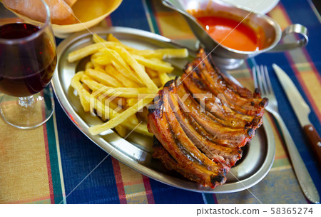 Grilled pork ribs with french fries, served with tomatoe sause Grilled pork ribs with french fries, served with tomatoe sause 58365274