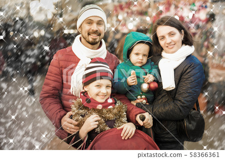 Cheerful parents with children choosing holidays decorations Cheerful parents with children choosing holidays decorations 58366361