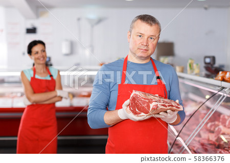 Positive man seller offering meat in shop Positive man seller offering meat in shop 58366376