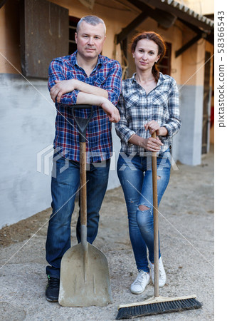 Smiling couple with tools standing at farm outdoor 58366543