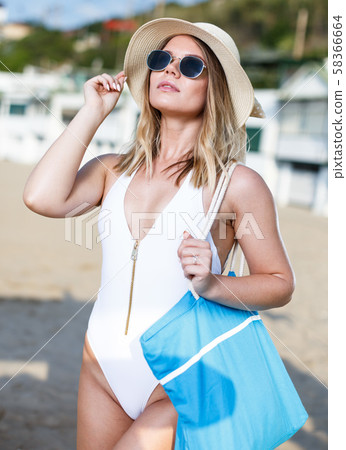 Young girl in swimsuit with bag walking from hotel to sea beach Young girl in swimsuit with bag walking from hotel to sea beach 58366664