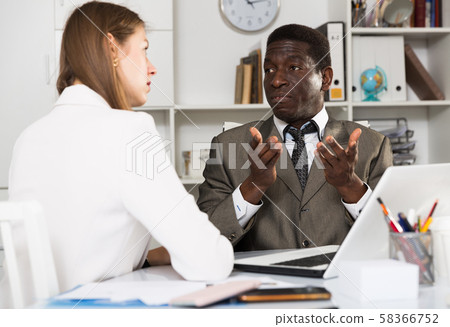 Young woman and man colleagues working at laptop and discussing Young woman and man colleagues working at laptop and discussing 58366752