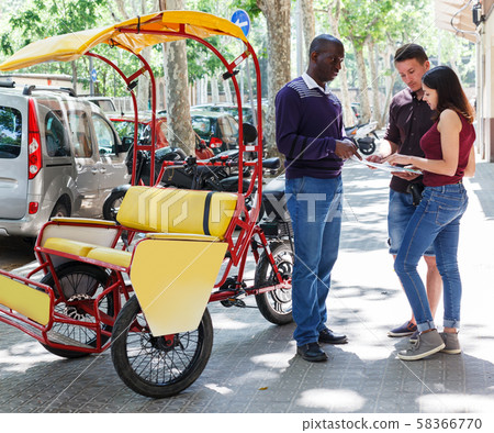 Pedicab driver negotiating with couple Pedicab driver negotiating with couple 58366770