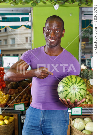 Portrait of man who is standing with watermelon in the fruit market. Portrait of man who is standing with watermelon in the fruit market. 58366793