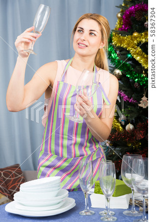 Cheerful girl is prepareing glasses for champagne befor New Year night 58367304