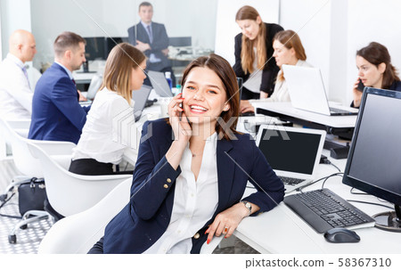Successful young business woman with phone relaxing at workplace in modern office Successful young business woman with phone relaxing at workplace in modern office 58367310