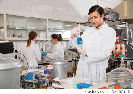 Focused young lab technician working with reagents in test tubes during chemical experiment 58367508