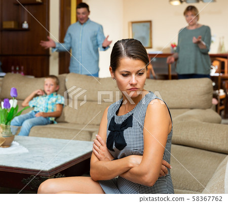 Upset woman sitting during quarrelling between family on background 58367762