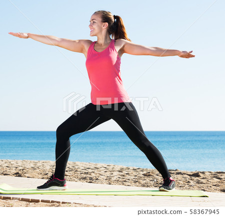 Woman doing yoga at beach Woman doing yoga at beach 58367945