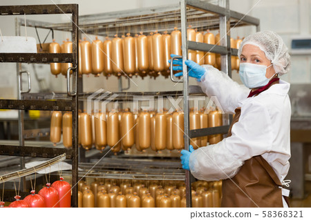 Female carrying sausages on racks Female carrying sausages on racks 58368321