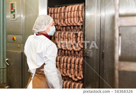 Woman checking sausages in baking machine Woman checking sausages in baking machine 58368326