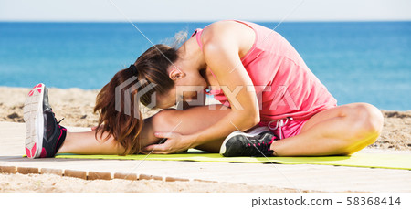 Woman doing yoga at beach 58368414