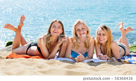 Portrait of three cheerful young women on beach Portrait of three cheerful young women on beach 58368416