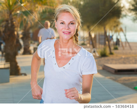 Female in white T-shirt is jogging Female in white T-shirt is jogging 58368418