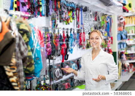 Female shop assistant showing leashes for pets Female shop assistant showing leashes for pets 58368601