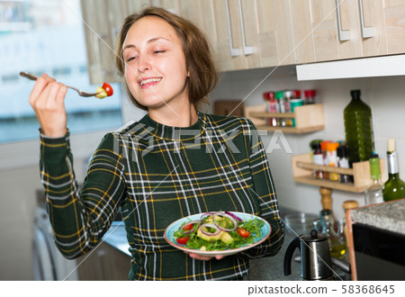 Woman standing with salad at kitchen Woman standing with salad at kitchen 58368645
