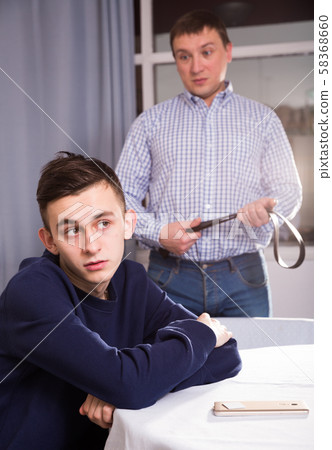 Man is angrying and wanting to punish him with strap 58368660
