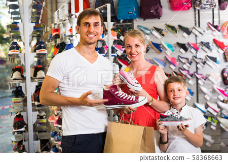 Family of three picking sport shoes in store. Family of three picking sport shoes in store. 58368663