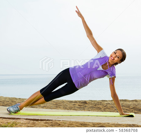 Woman doing exercises on beach by ocean Woman doing exercises on beach by ocean 58368708