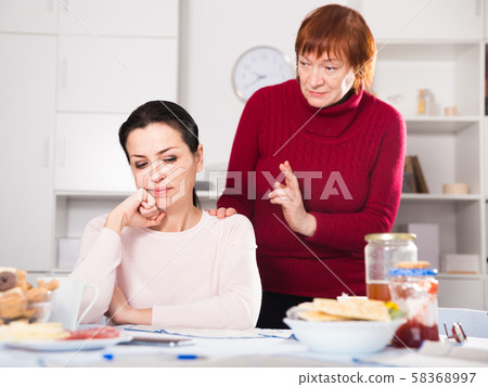 Upset woman quarrel with mother at table 58368997