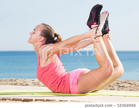 Positive young sporty woman exercising 58368998