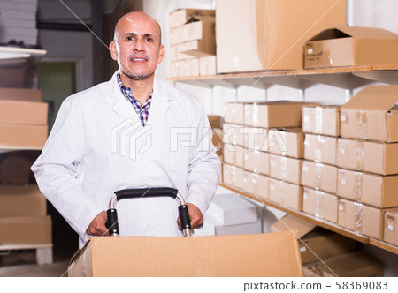 Mature male worker standing with cart at workplace Mature male worker standing with cart at workplace 58369083