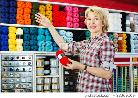 Mature glad woman customer picking various yarn Mature glad woman customer picking various yarn 58369109