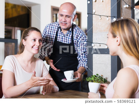 Two young girls meeting in cafe and drinking tasty coffee 58369121