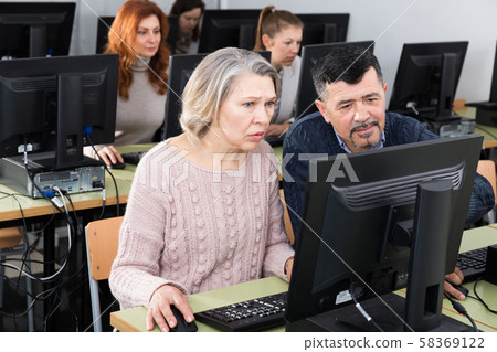 Mature man and woman learning to use computer Mature man and woman learning to use computer 58369122