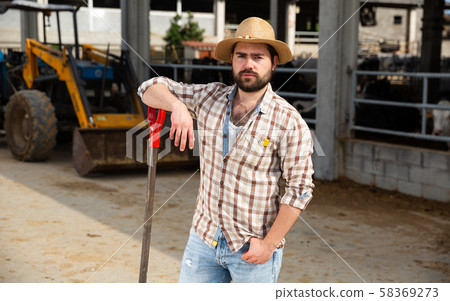 Young man farmer with shovel standing near agrimotor 58369273