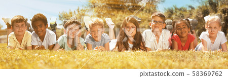 Happy children lie on the green grass on a sunny day Happy children lie on the green grass on a sunny day 58369762
