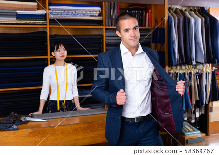 Elegant man trying on new suit in clothing store 58369767