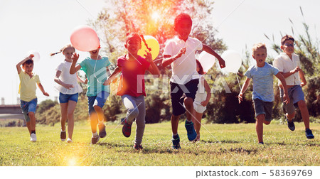 Cheerful kids with balloons are jogging together in the park and having fun Cheerful kids with balloons are jogging together in the park and having fun 58369769