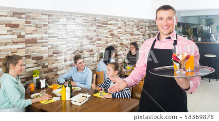 waiter warmly welcoming guests to cozy family cafe 58369878