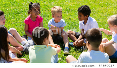 Group of elementary school children chatting on the green lawn Group of elementary school children chatting on the green lawn 58369937