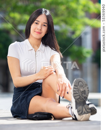 Teenage girl sitting at stone bench in park at summer day Teenage girl sitting at stone bench in park at summer day 58369940