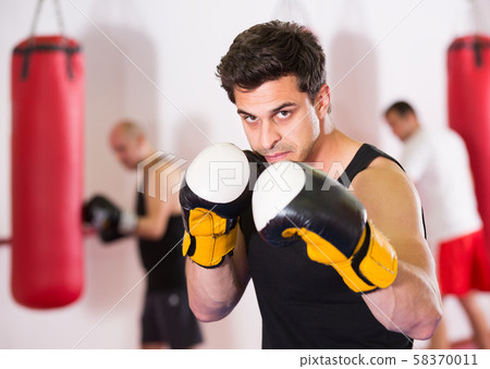 active sportsman in the boxing hall practicing boxing punches active sportsman in the boxing hall practicing boxing punches 58370011