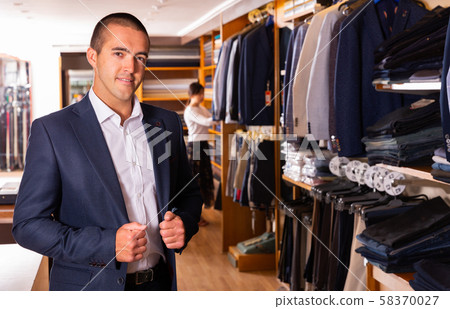 Portrait of male client choosing classic jacket in the mall Portrait of male client choosing classic jacket in the mall 58370027