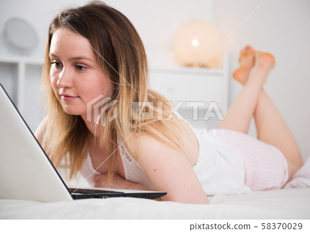 Attractive young woman lying with laptop in bed at home 58370029