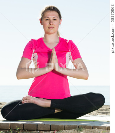 Woman training yoga poses on beach Woman training yoga poses on beach 58370068