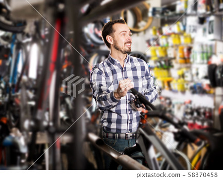 Man considers bicycle handlebar in store Man considers bicycle handlebar in store 58370458