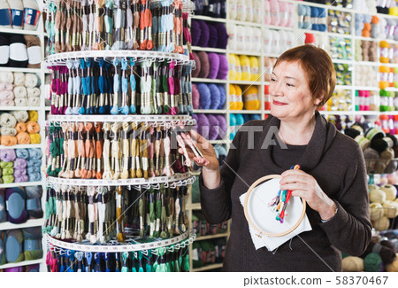 Woman choosing mouline for embroidery in needlework shop Woman choosing mouline for embroidery in needlework shop 58370467
