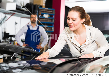 Woman admiring car after repainting Woman admiring car after repainting 58370663