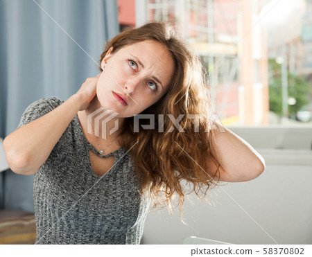Woman holding hands on her sore neck Woman holding hands on her sore neck 58370802