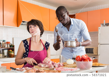 Bored woman cooking with displeased husband Bored woman cooking with displeased husband 58371021