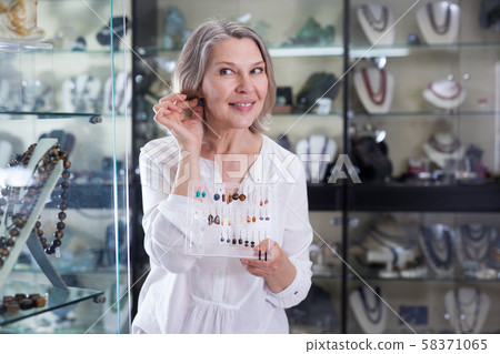 Adult woman chooses jewelry from turquoise jewelery in the store Adult woman chooses jewelry from turquoise jewelery in the store 58371065