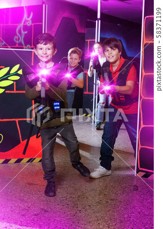 Emotional teen boy with laser pistol playing laser tag with frie Emotional teen boy with laser pistol playing laser tag with frie 58371199