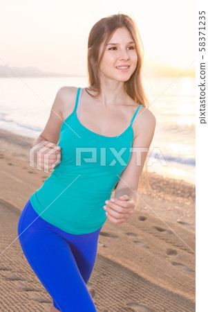 Smiling adult woman in blue T-shirt is jogging 58371235