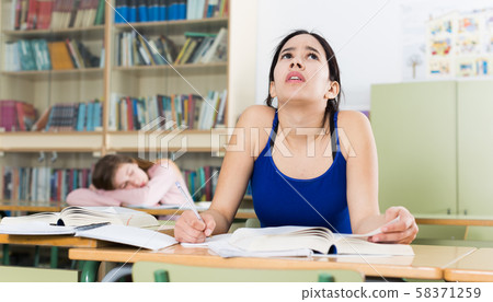 Girl is pondering about complicated task at the desk Girl is pondering about complicated task at the desk 58371259