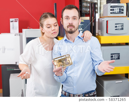 Upset girl with boyfriend looking for new reliable door lock in store 58371265